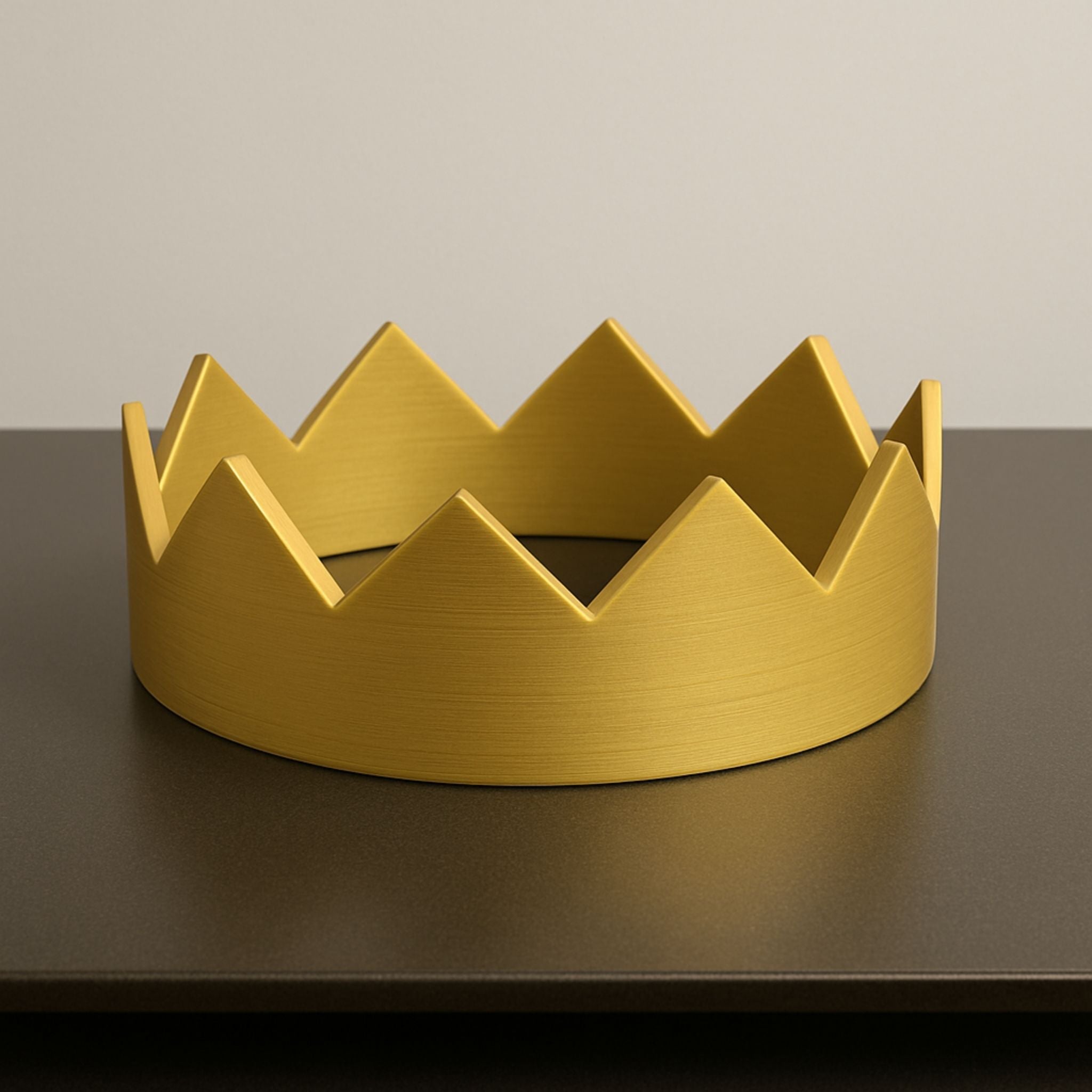 Gold crown-shaped object on a dark surface with a neutral background