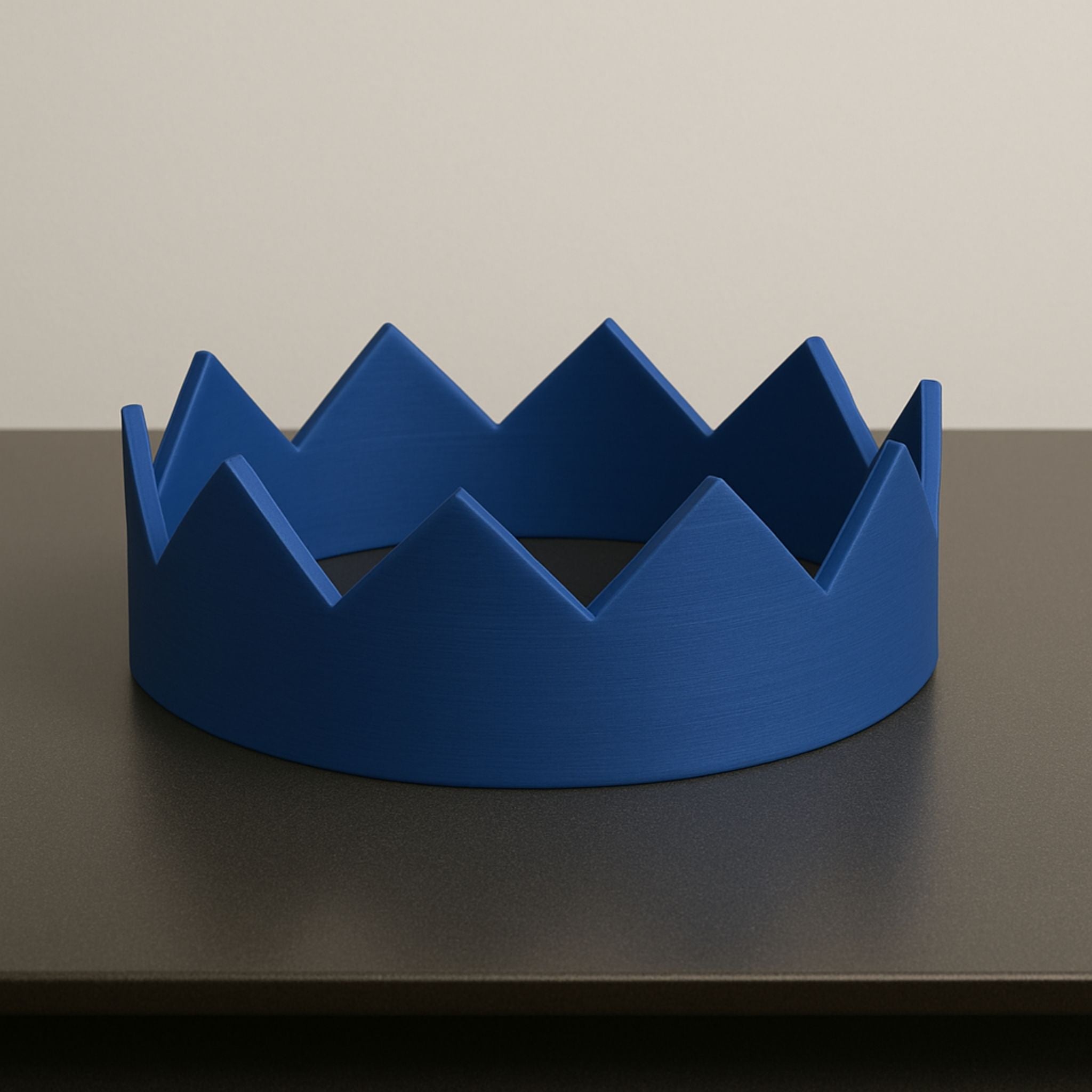 Blue crown-shaped object on a dark surface with a neutral background