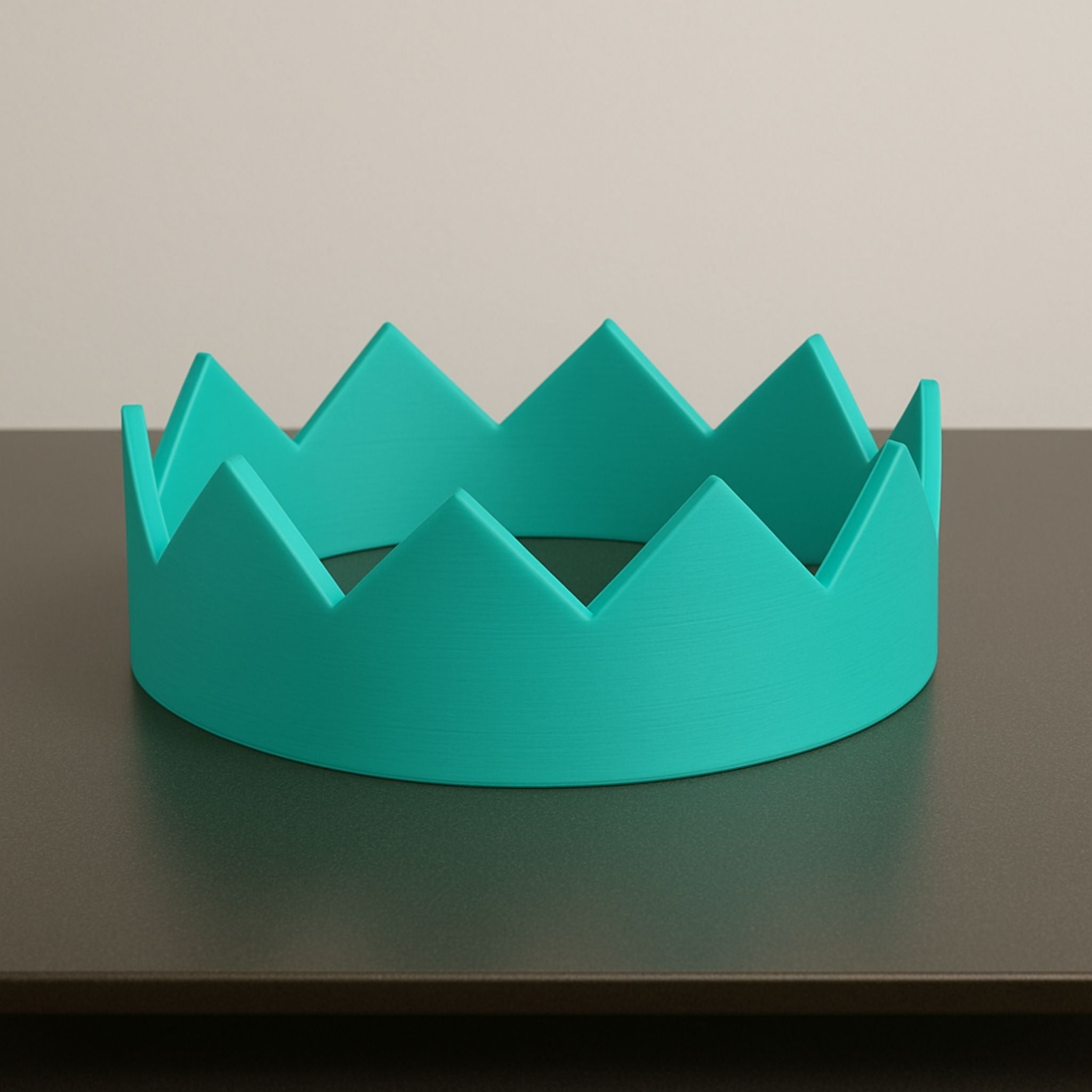 Turquoise crown-shaped object on a dark surface with a beige background