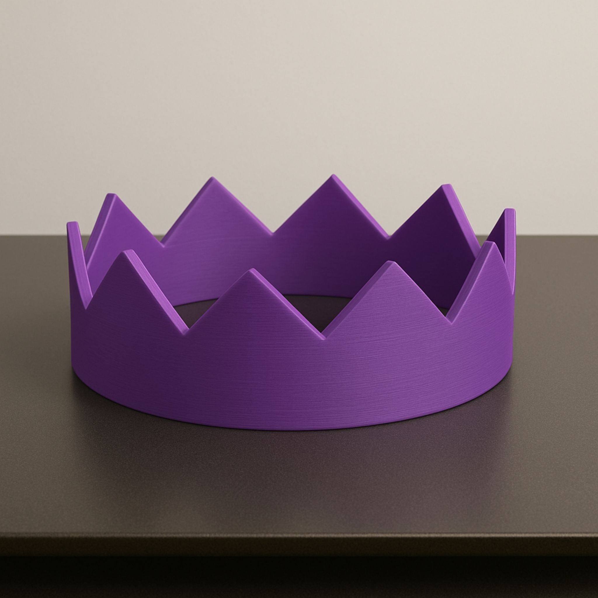 Purple crown-shaped object on a dark surface with a neutral background