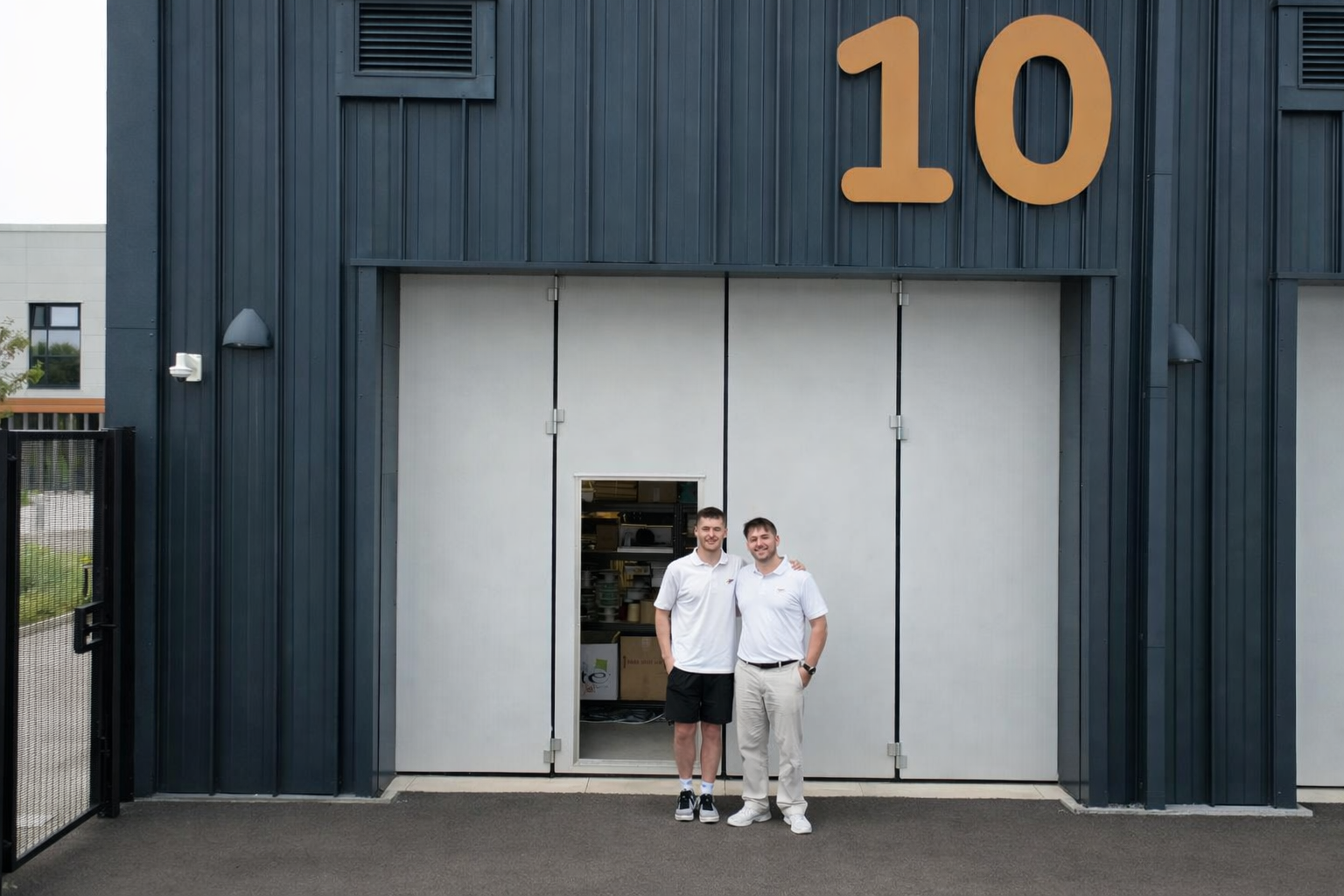 Two men standing in front of a building with the number 10 on it.